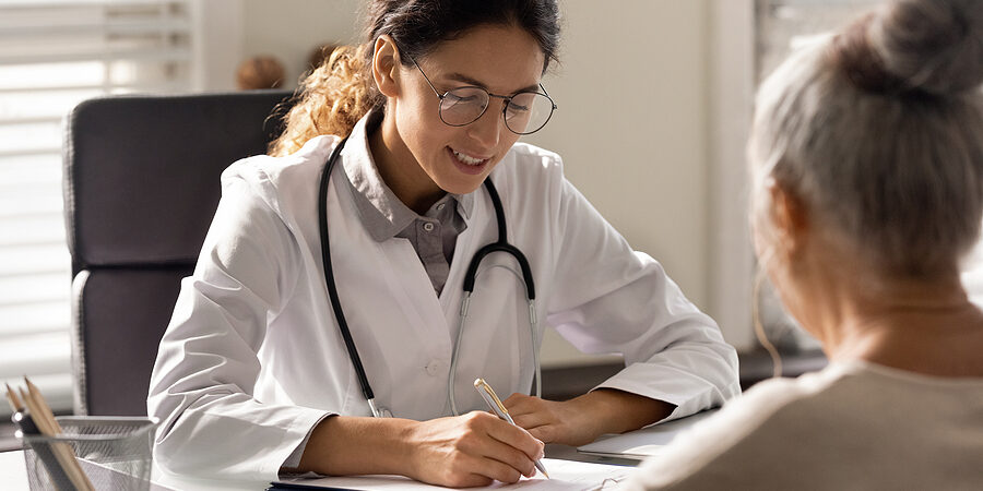 Female Doctor Write Prescription To Elderly Patient